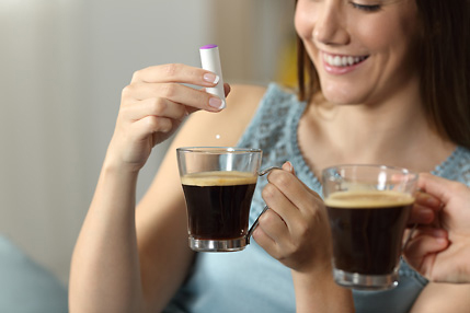 Kaffeetrinkerin mit Süßstoffspender